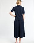 Woman wearing a navy blue outfit with a skirt on a white background