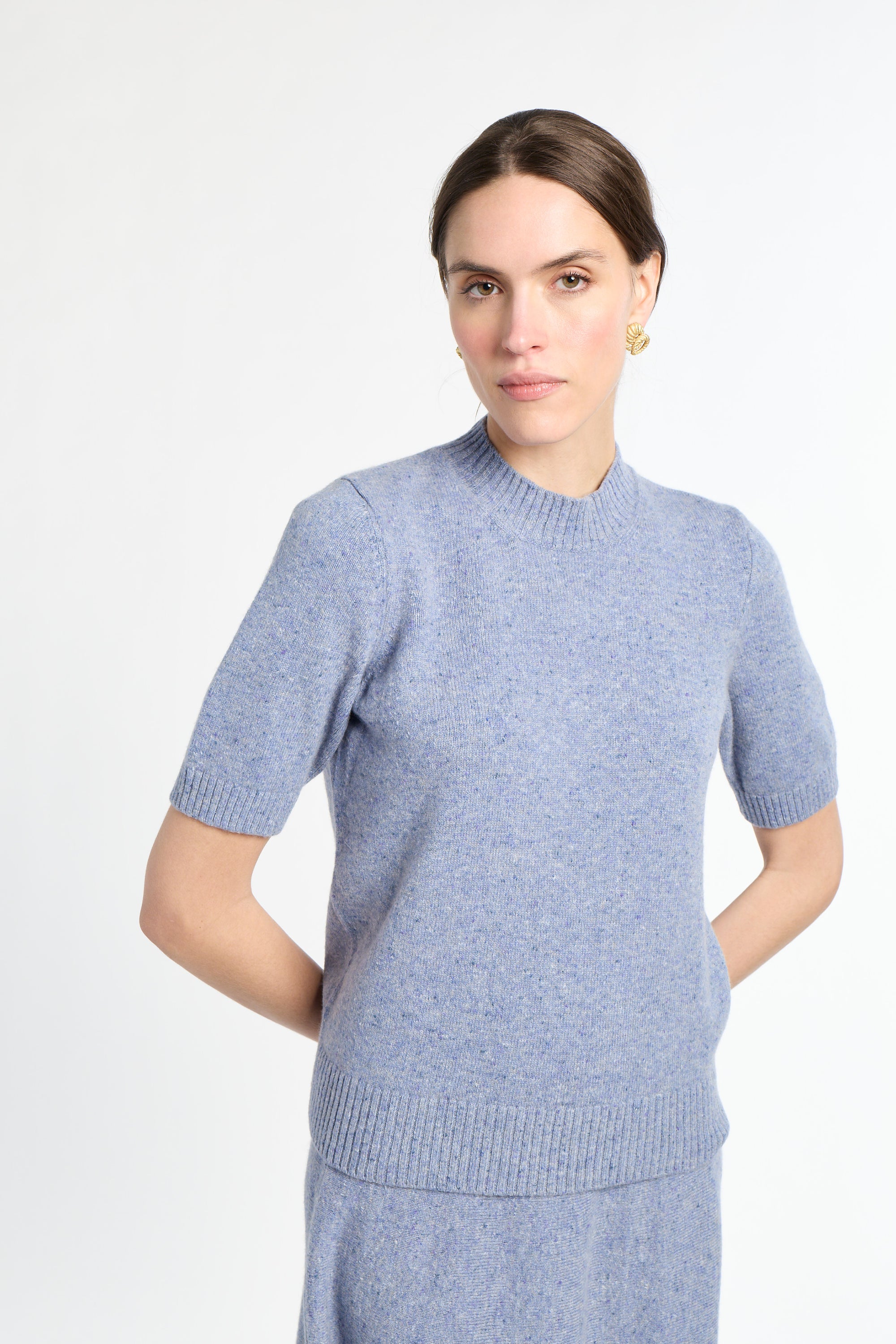 Woman wearing a light blue sweater dress against a white background