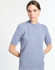 Woman wearing a light blue sweater dress against a white background