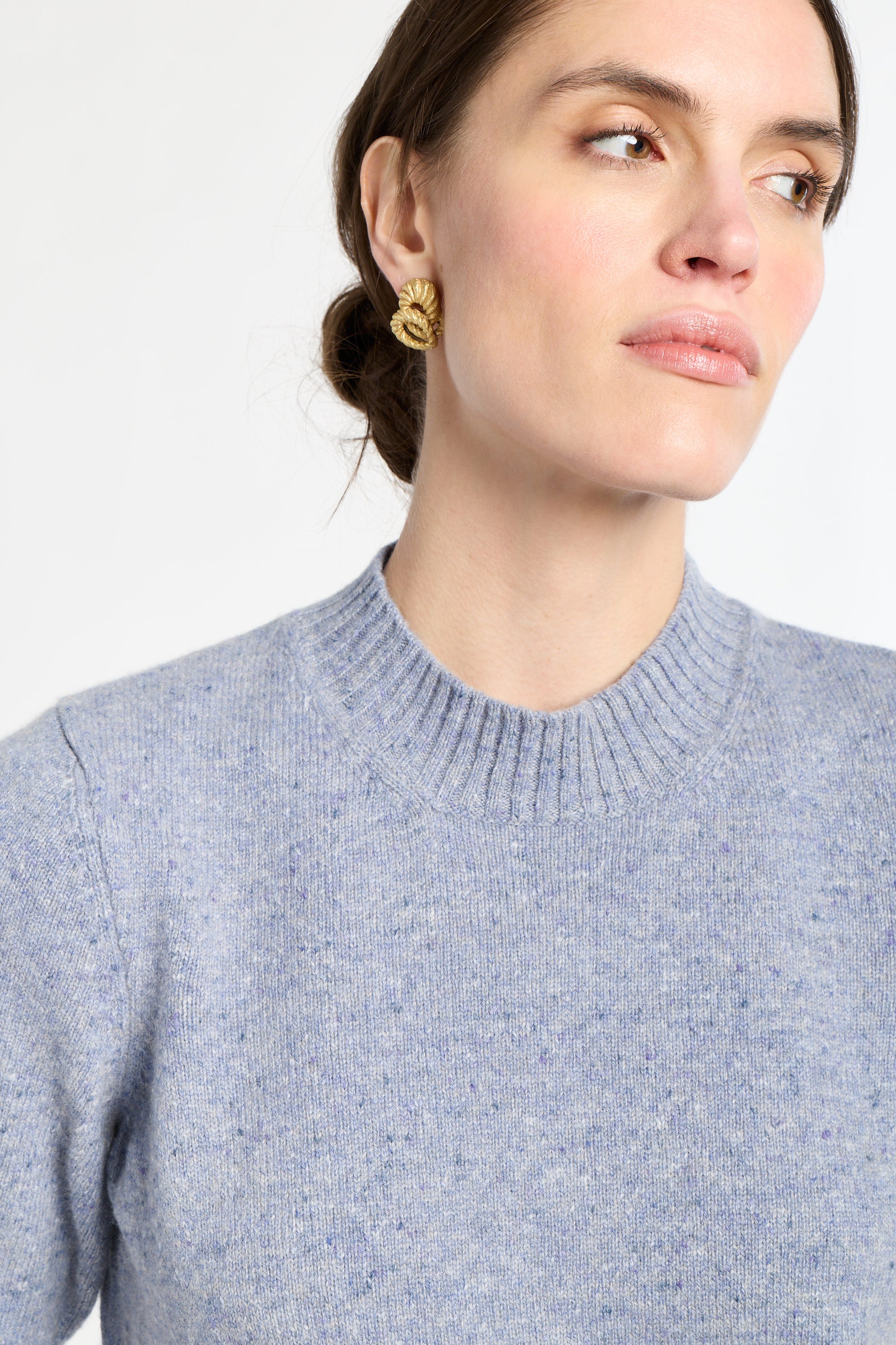 Woman wearing a gray sweater against a white background