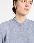 Woman wearing a gray sweater against a white background