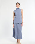 Woman with sleeveless blue sweater on with matching blue knit skirt. 