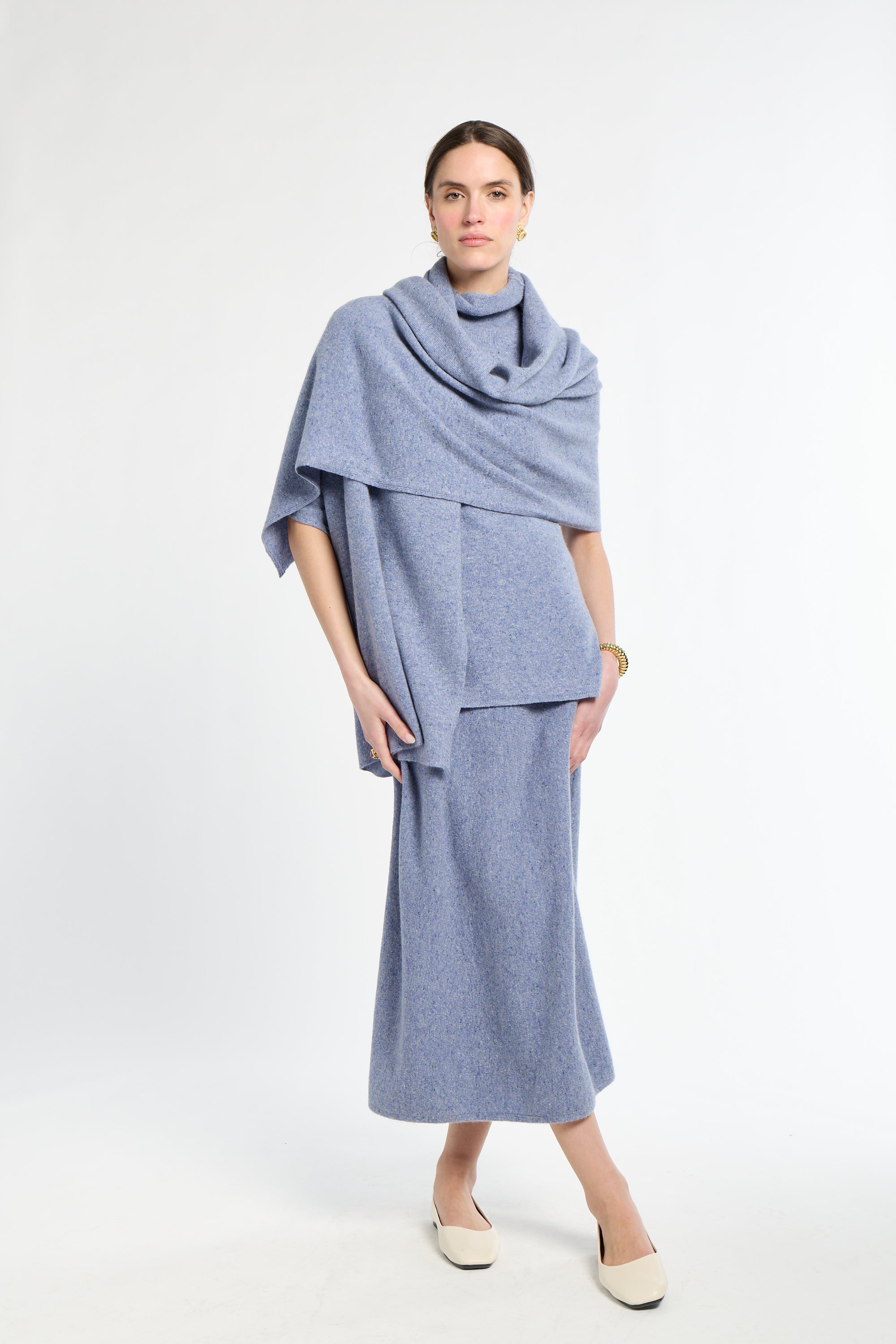 Woman wearing a light blue outfit with a matching scarf on a white background