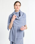 Woman wearing a light blue scarf and dress against a white background