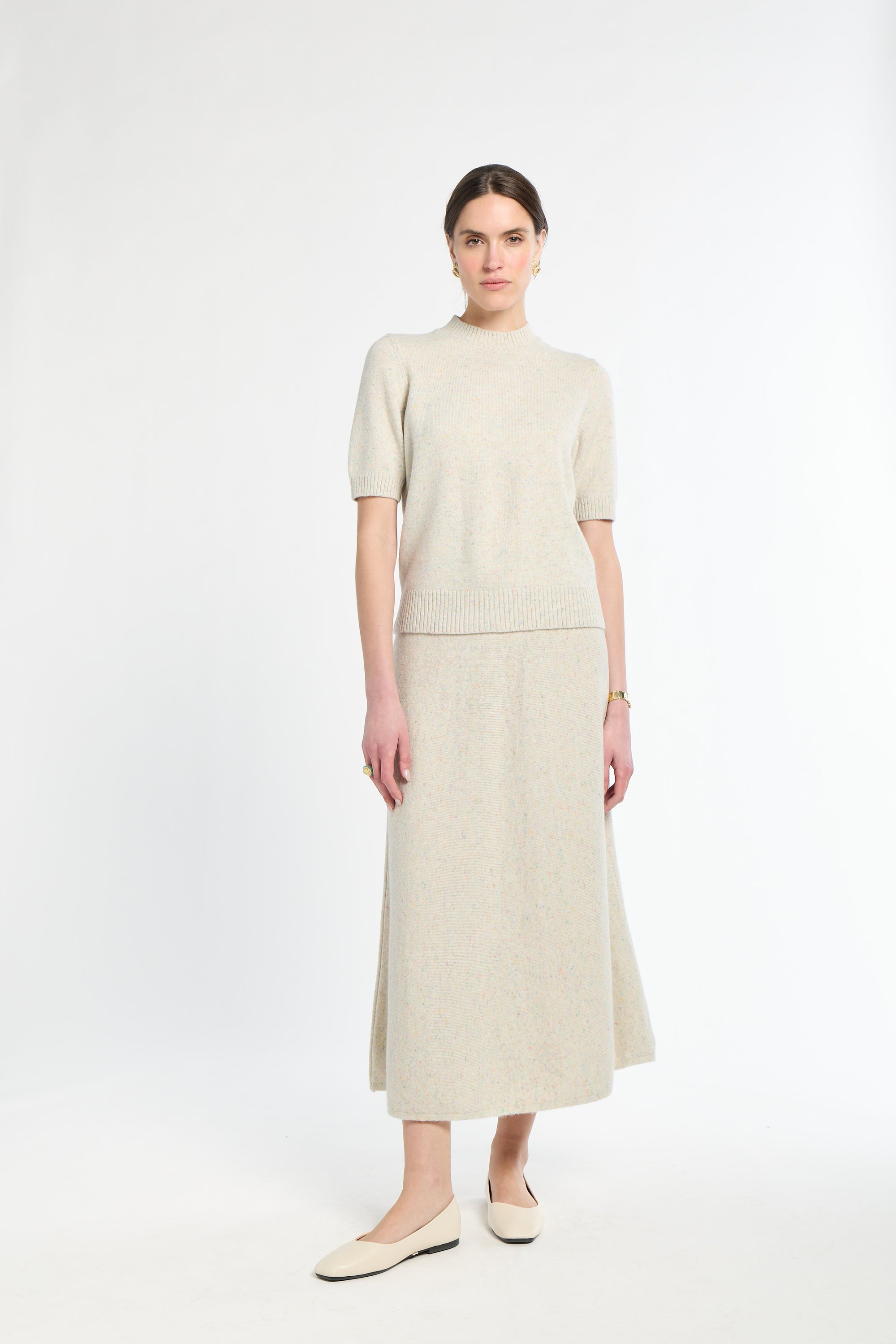 Woman wearing a beige outfit with a top and skirt on a white background