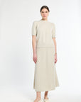 Woman wearing a beige outfit with a top and skirt on a white background
