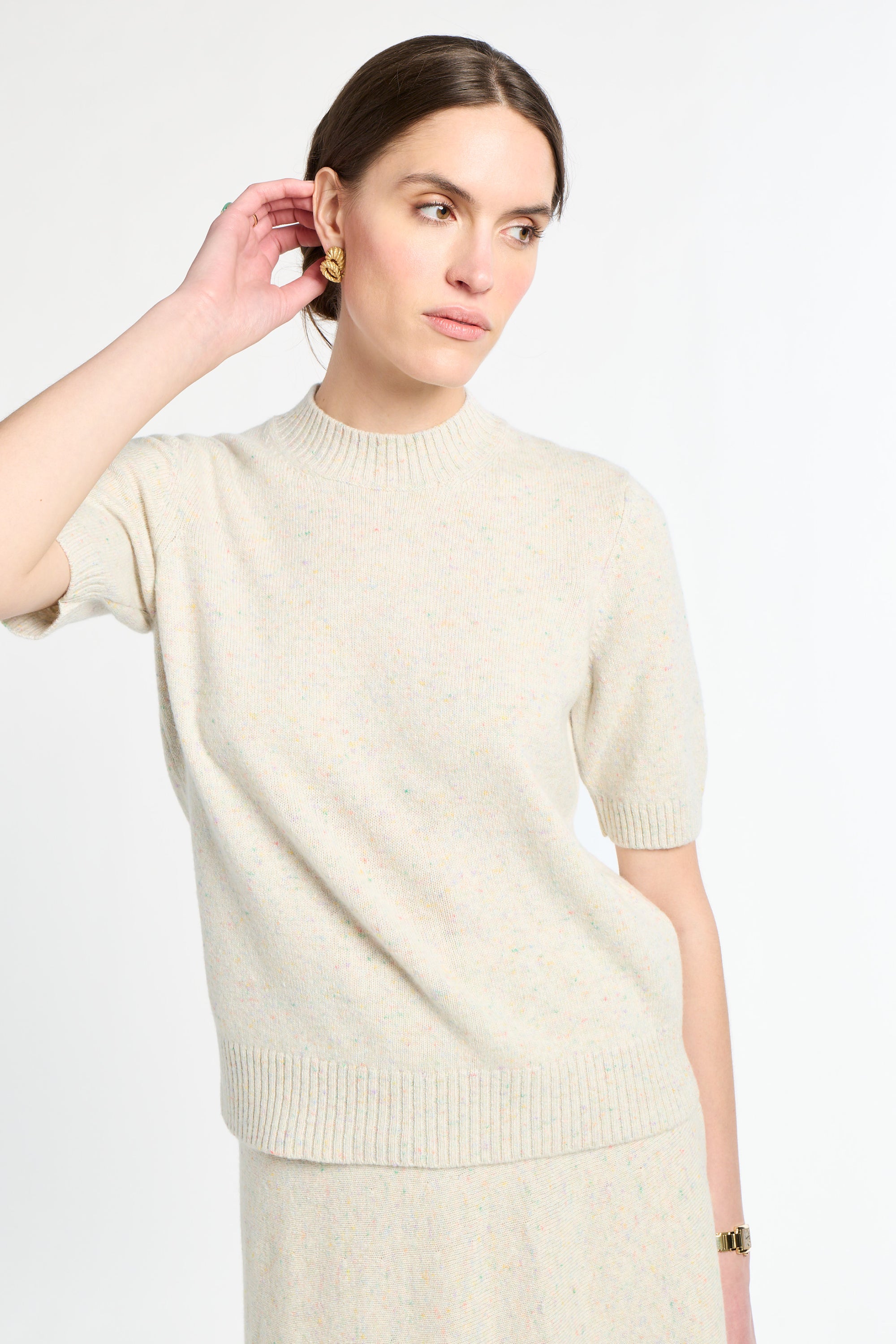 Woman wearing a cream sweater against a white background