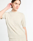 Woman wearing a cream sweater against a white background