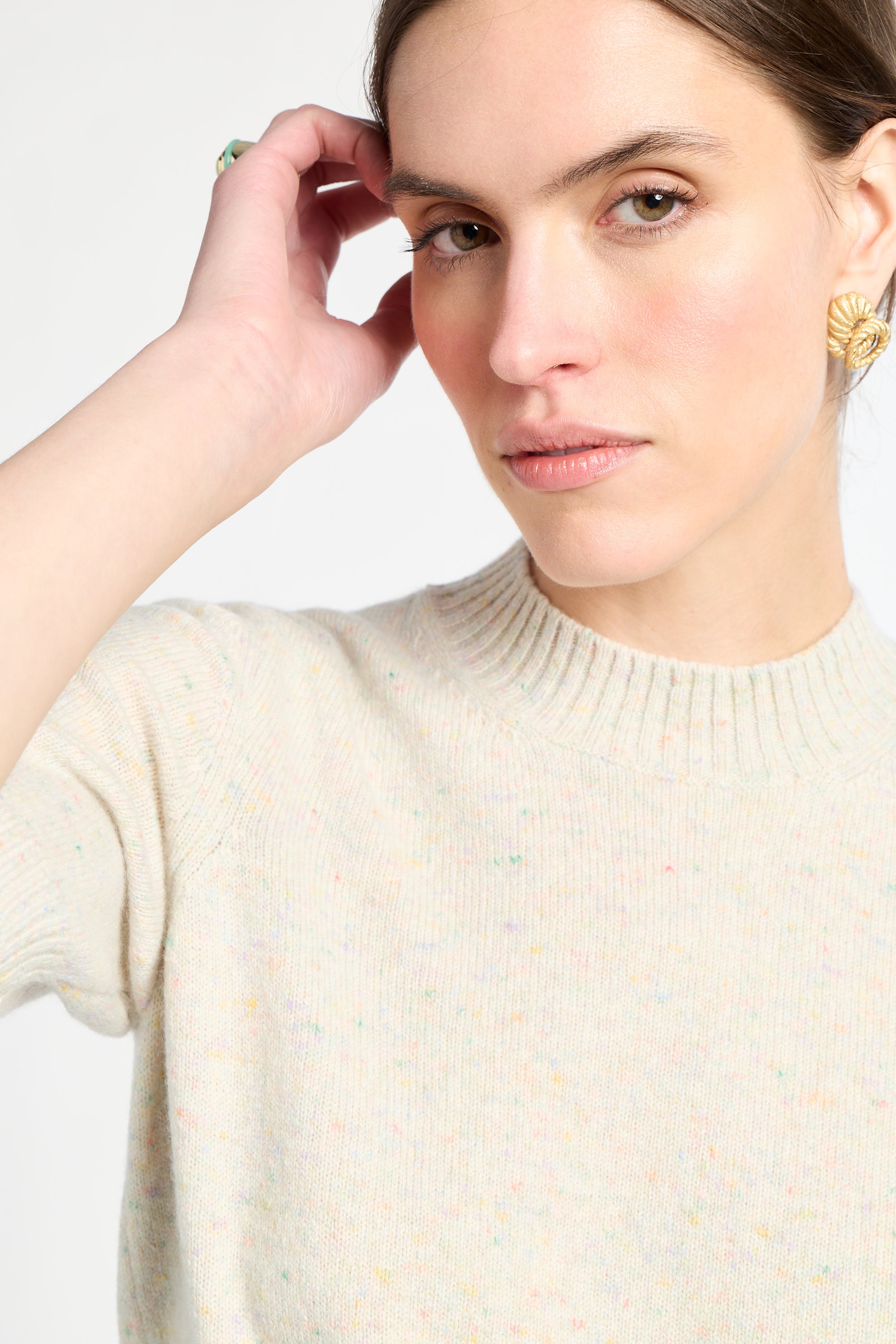 Woman wearing a cream sweater against a light background