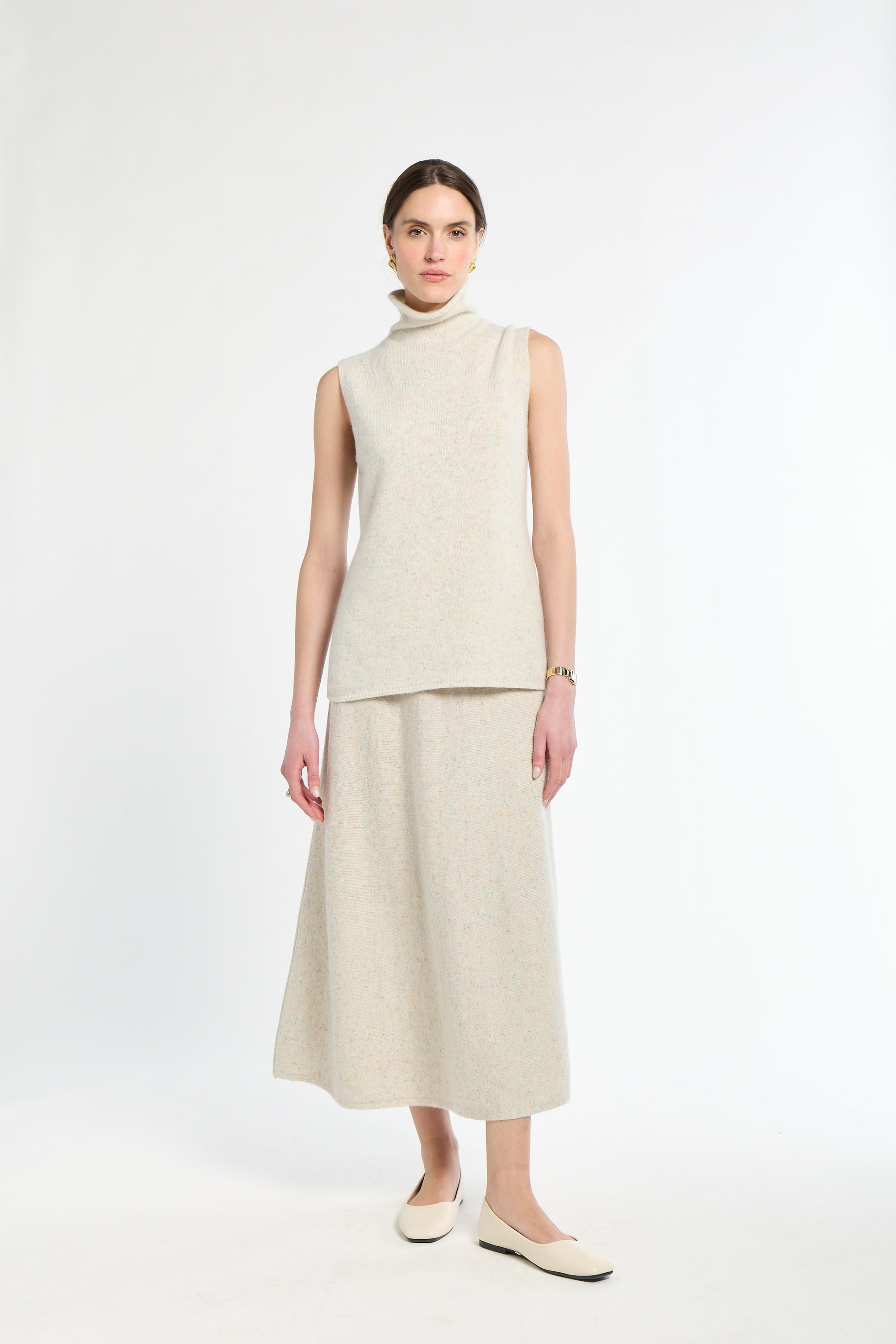 Woman wearing a beige sleeveless top and skirt set on a white background