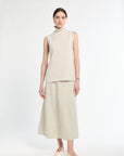 Woman wearing a beige sleeveless top and skirt set on a white background