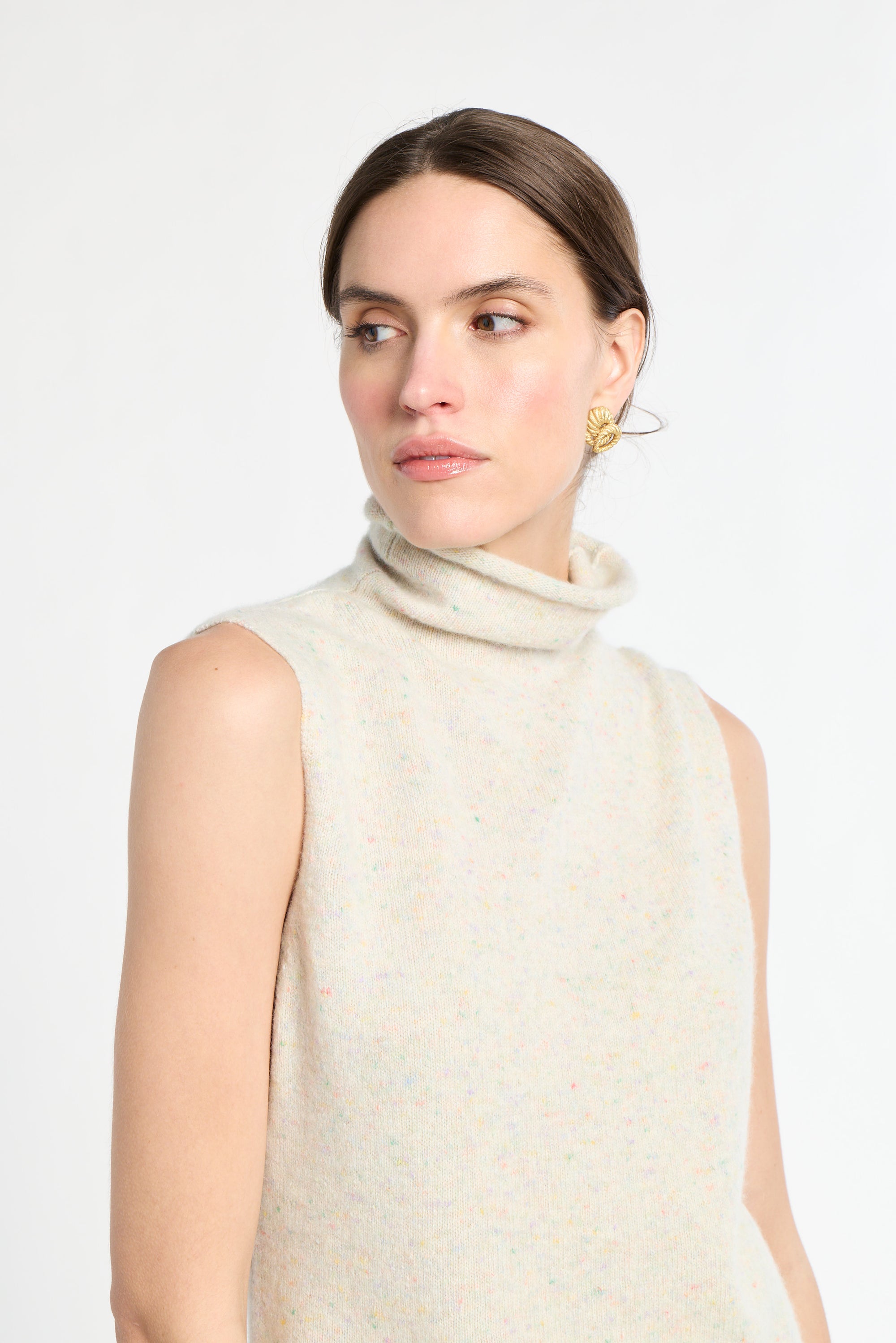 Woman wearing a beige sleeveless sweater on a white background