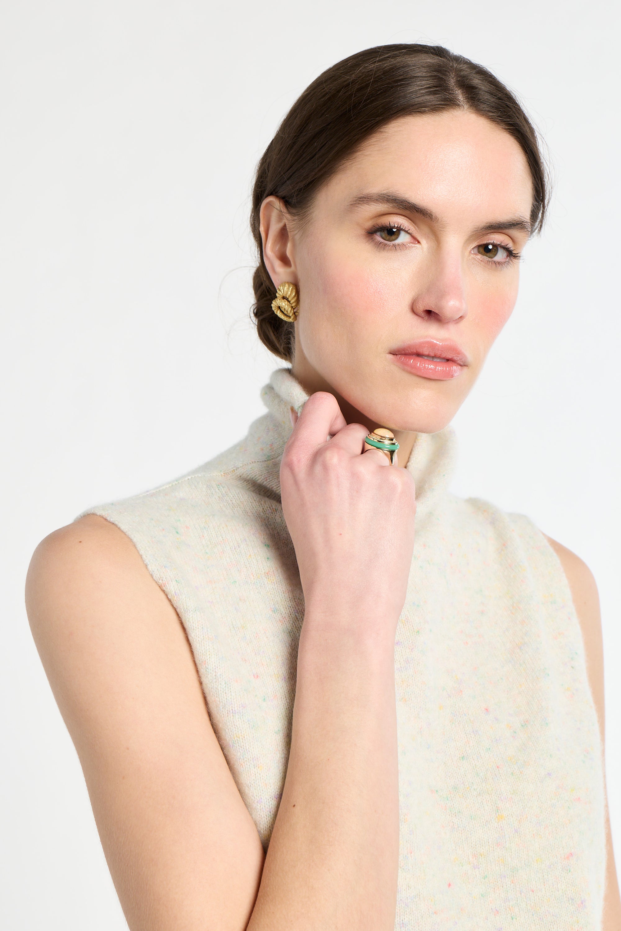 Woman wearing a white sleeveless sweater with a plain background