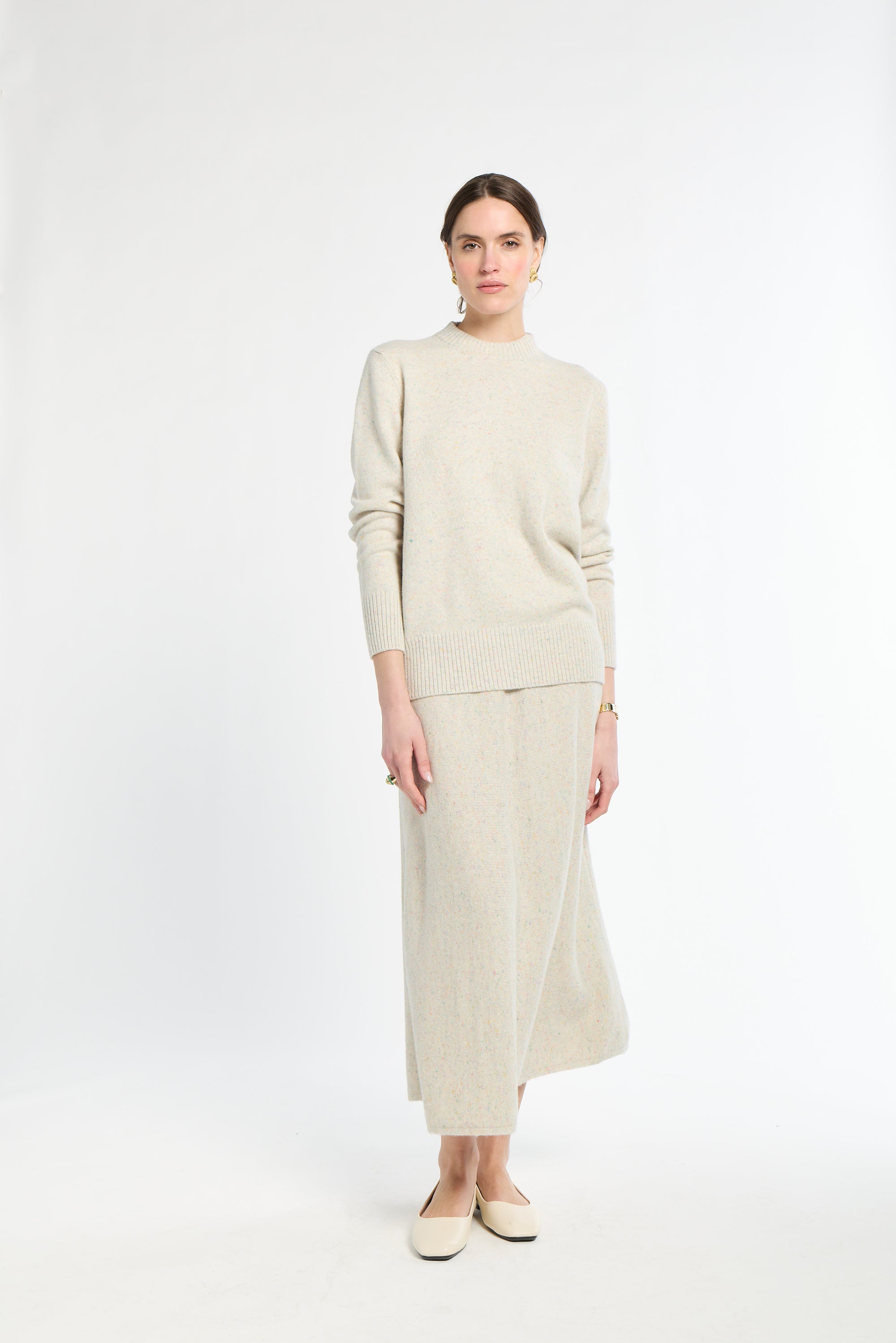 Woman wearing a beige sweater and skirt set on a white background
