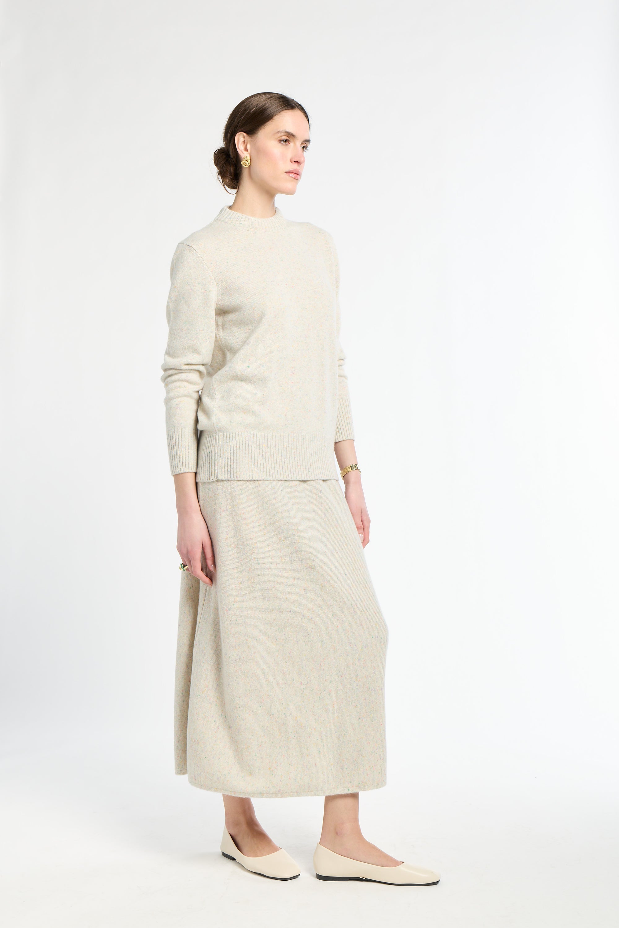 Woman wearing a beige sweater and skirt set on a white background