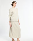 Woman wearing a beige sweater and skirt set on a white background