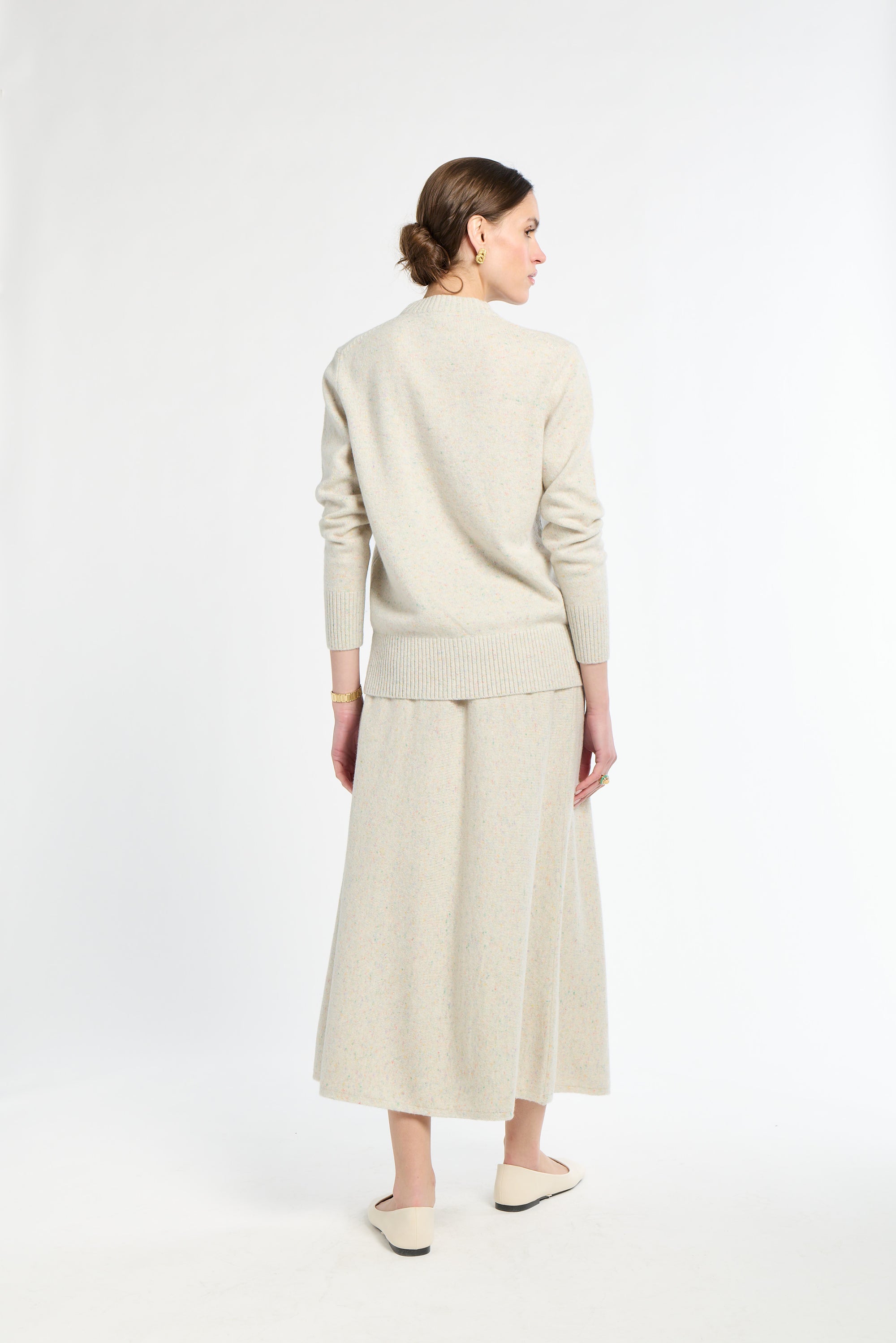 Woman wearing a beige sweater and skirt set on a white background