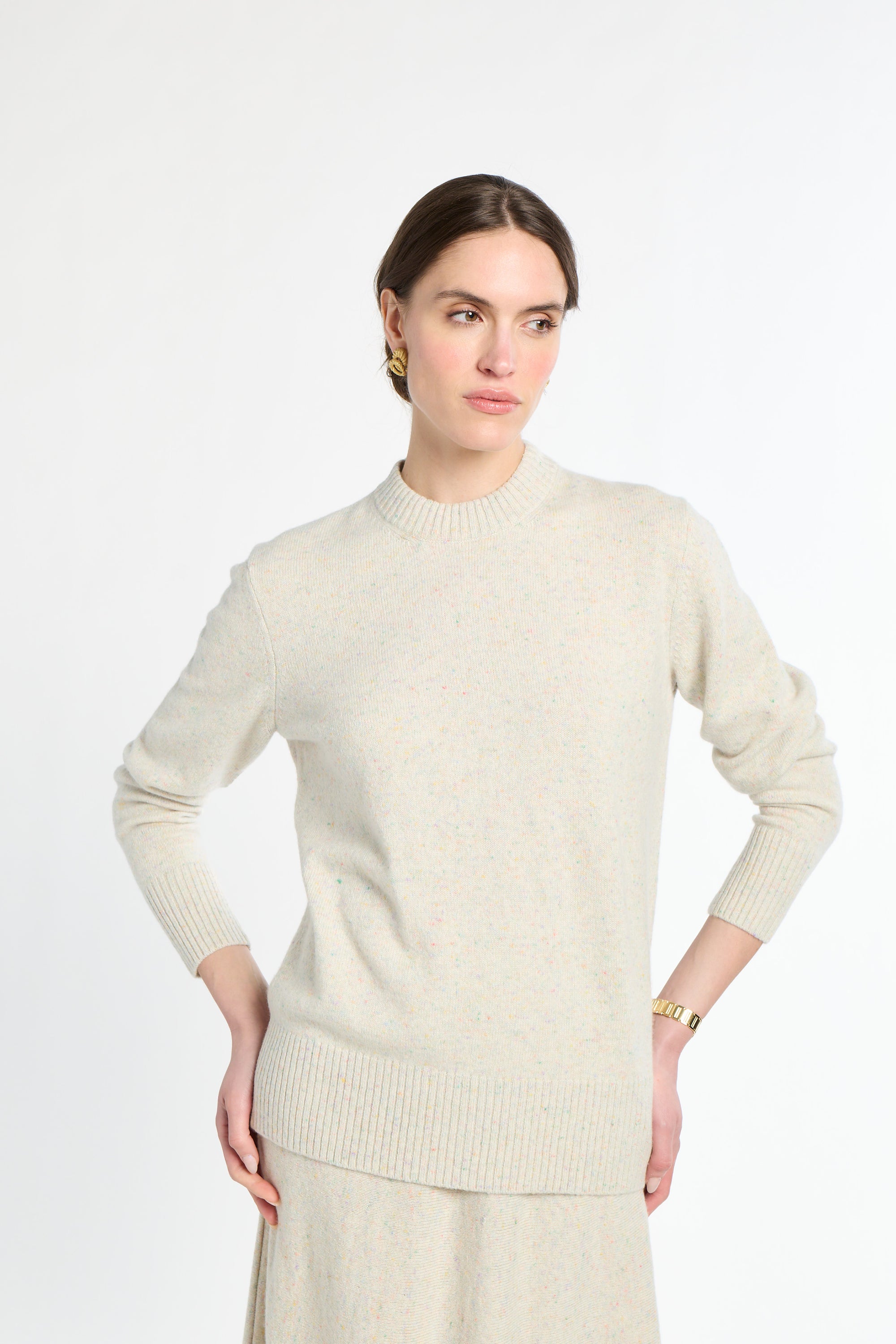 Woman wearing a light beige sweater against a white background