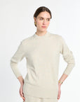Woman wearing a light beige sweater against a white background