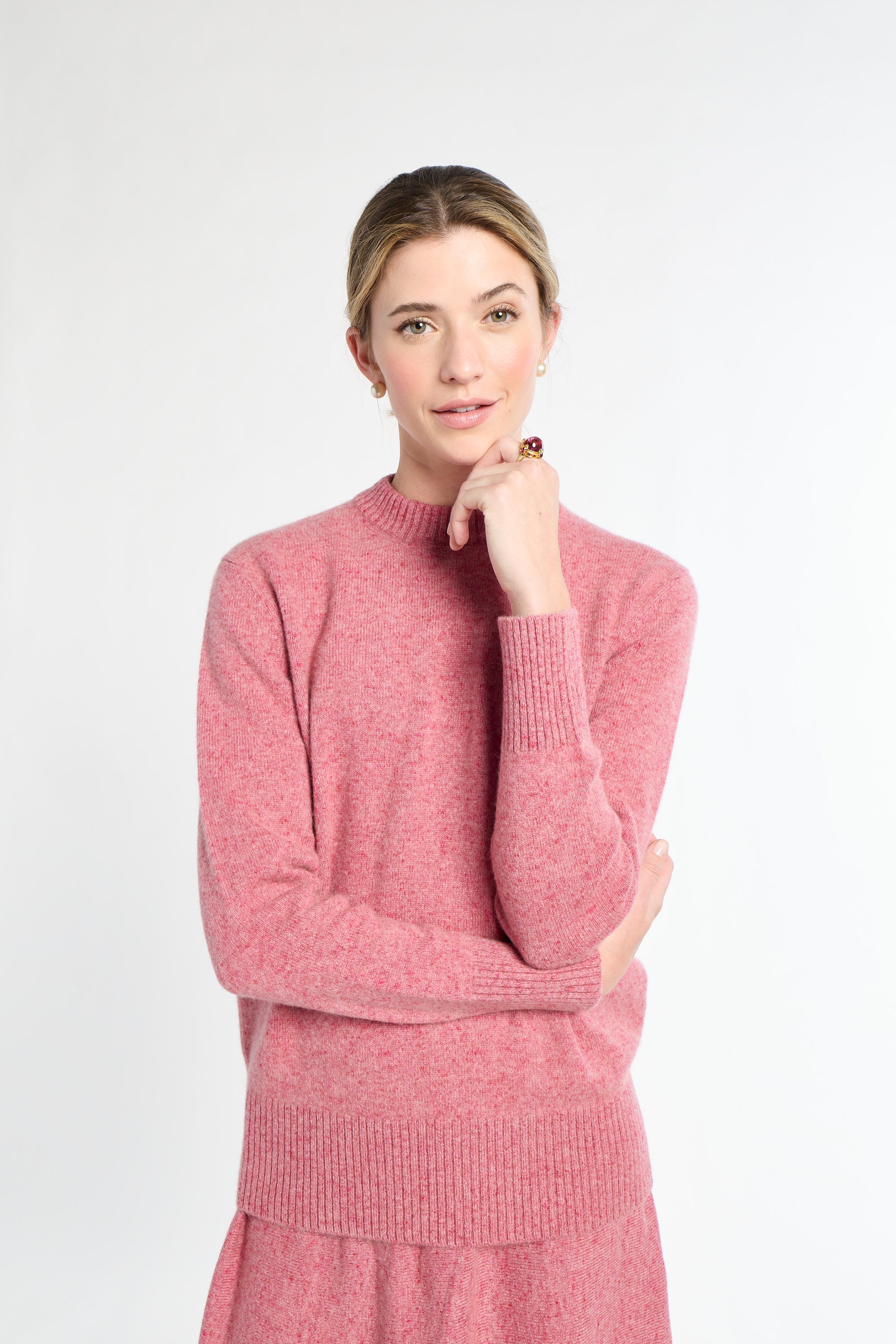 Woman wearing a pink sweater and skirt on a white background