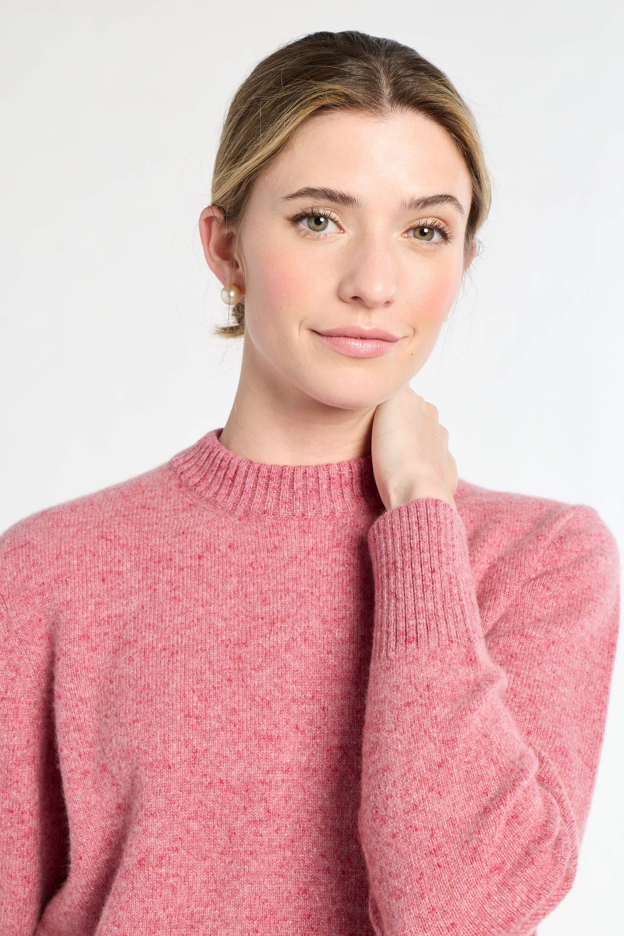 Woman wearing a pink sweater against a white background