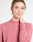Woman wearing a pink sweater against a white background