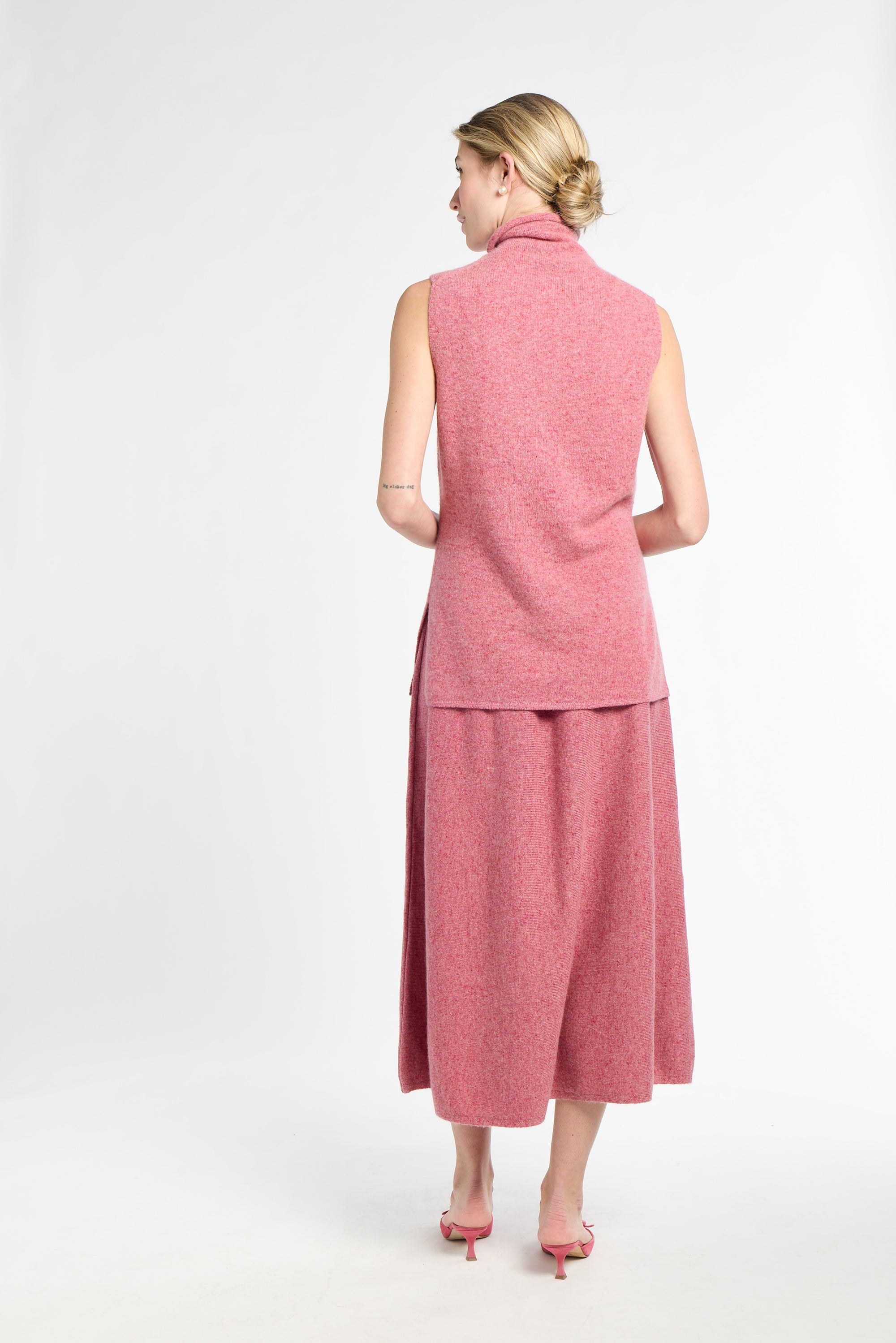 Woman wearing a pink sleeveless top and skirt set on a white background