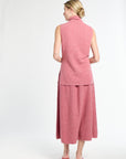 Woman wearing a pink sleeveless top and skirt set on a white background