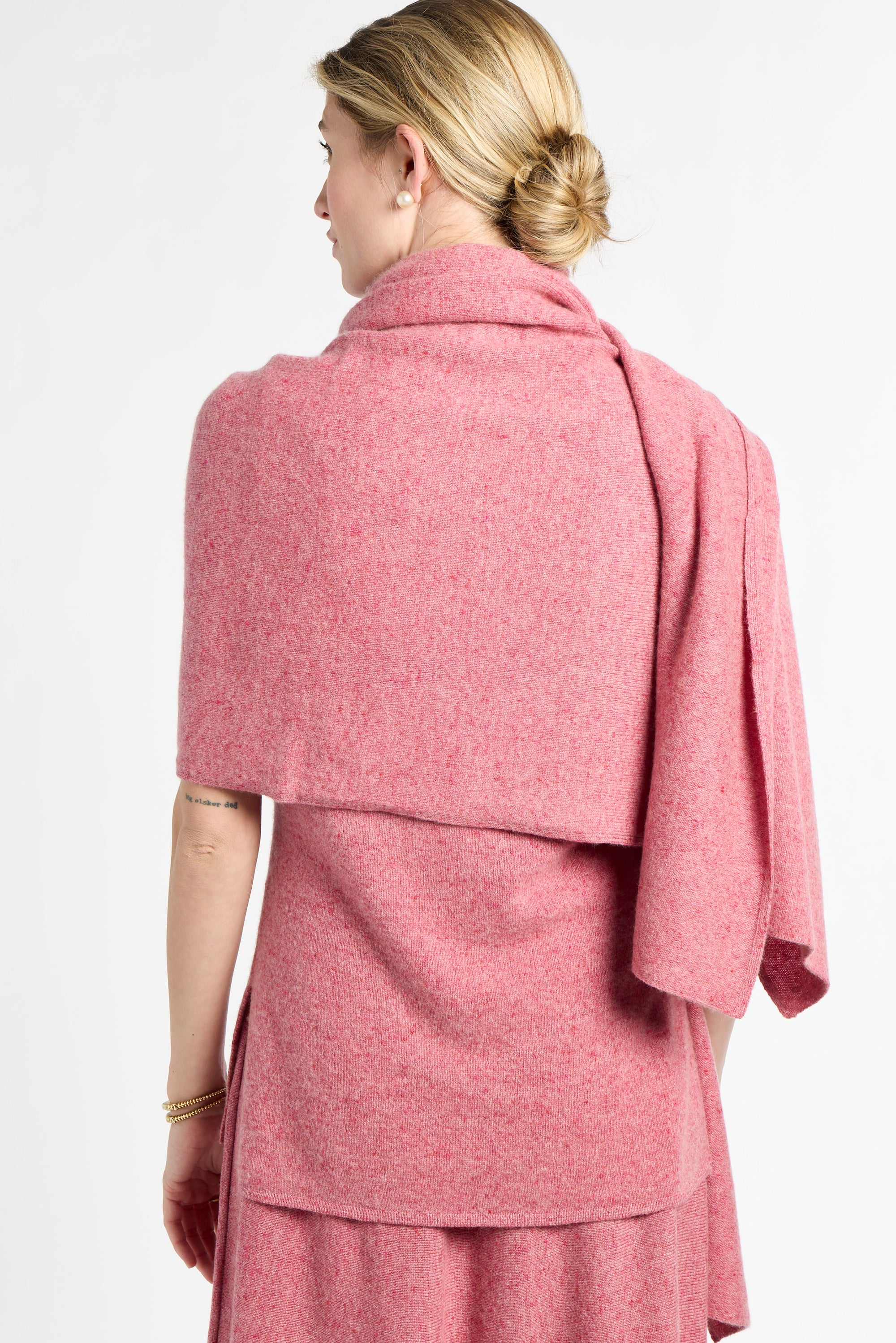 Woman wearing a pink shawl over a dress on a white background