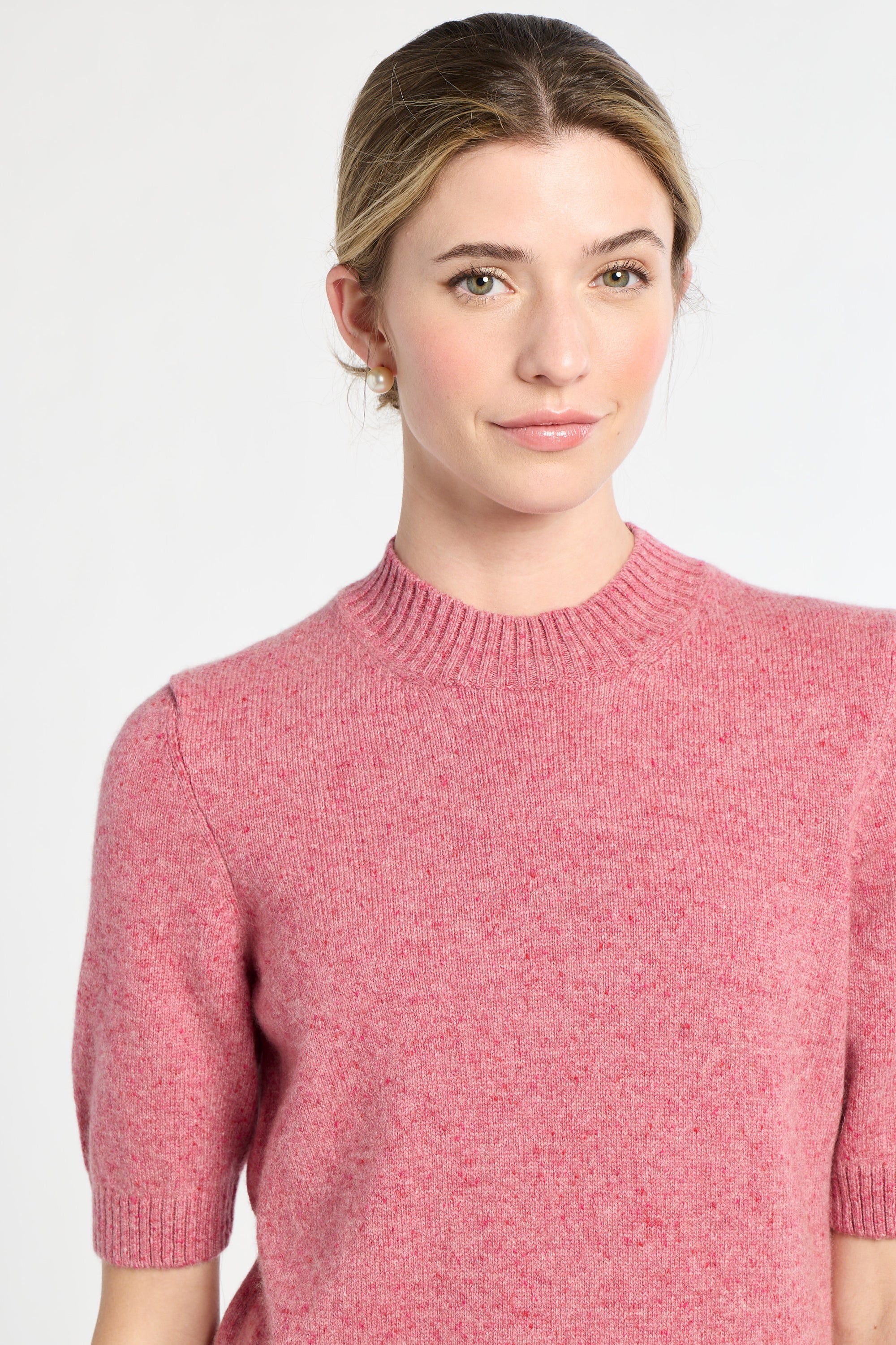 Woman wearing a pink sweater against a white background