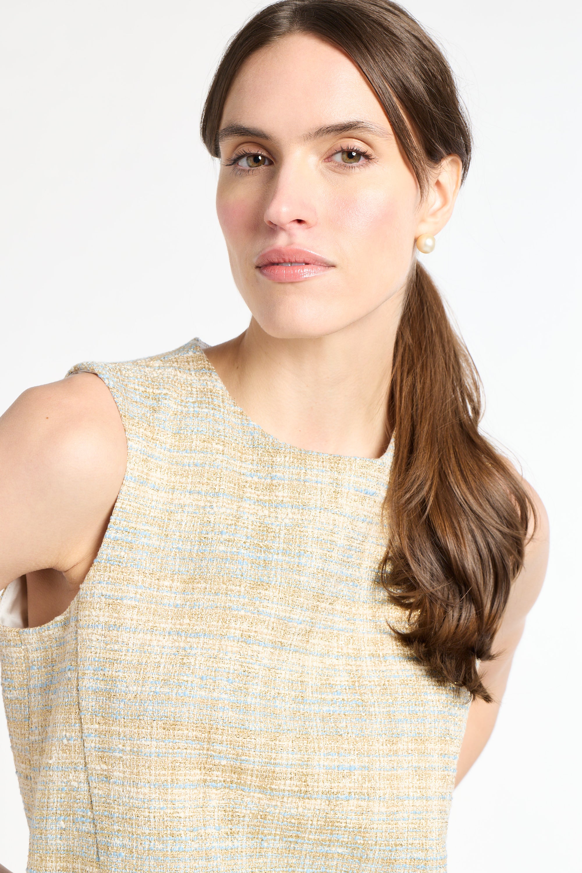Woman wearing a sleeveless tweed shirt on a white background