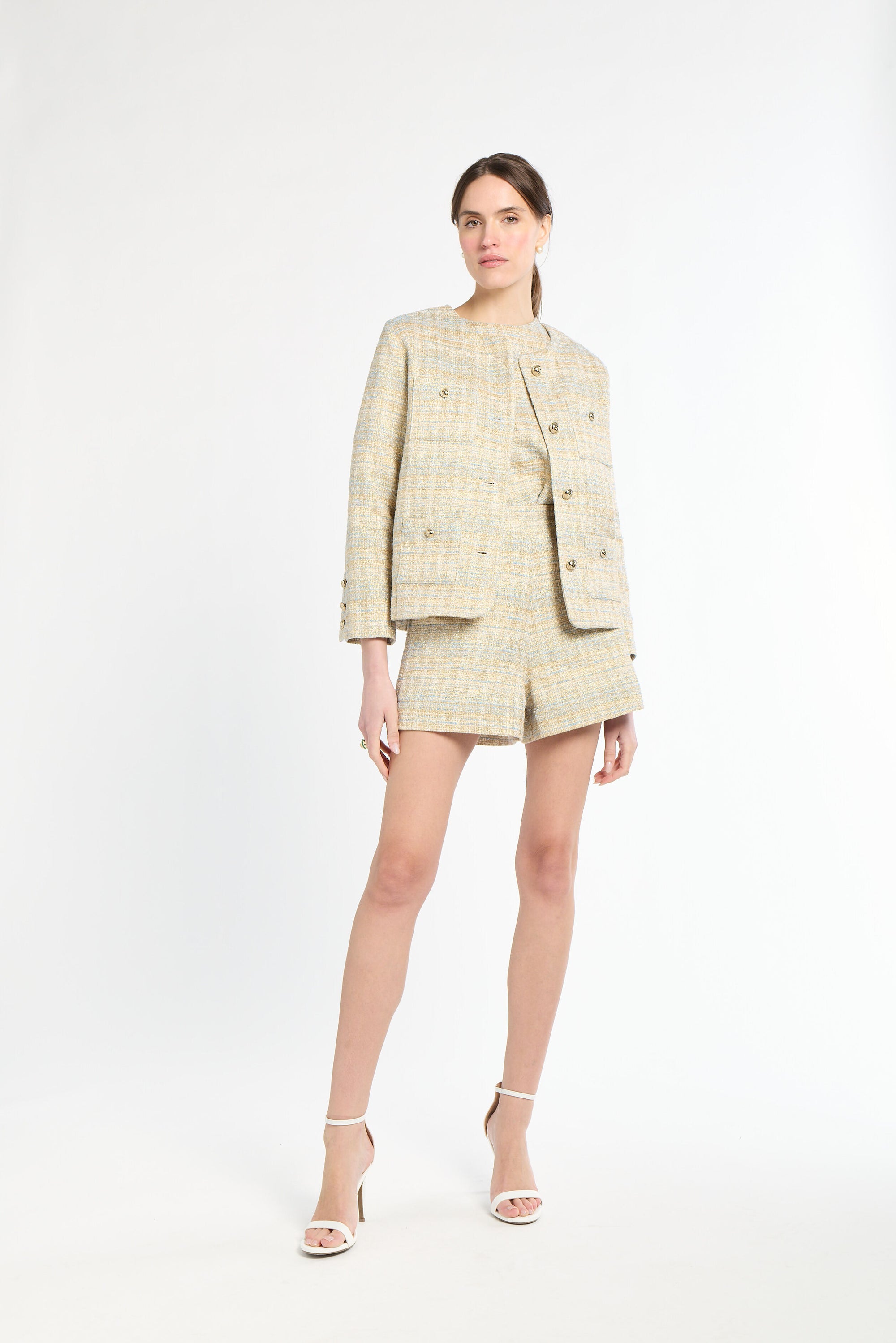 Woman wearing a golden and light blue tweed set on a white background