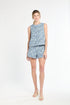 Woman wearing a sleeveless blue tweed top and shorts on a white background