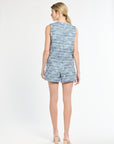 Back of woman wearing a sleeveless blue tweed top and shorts on a white background