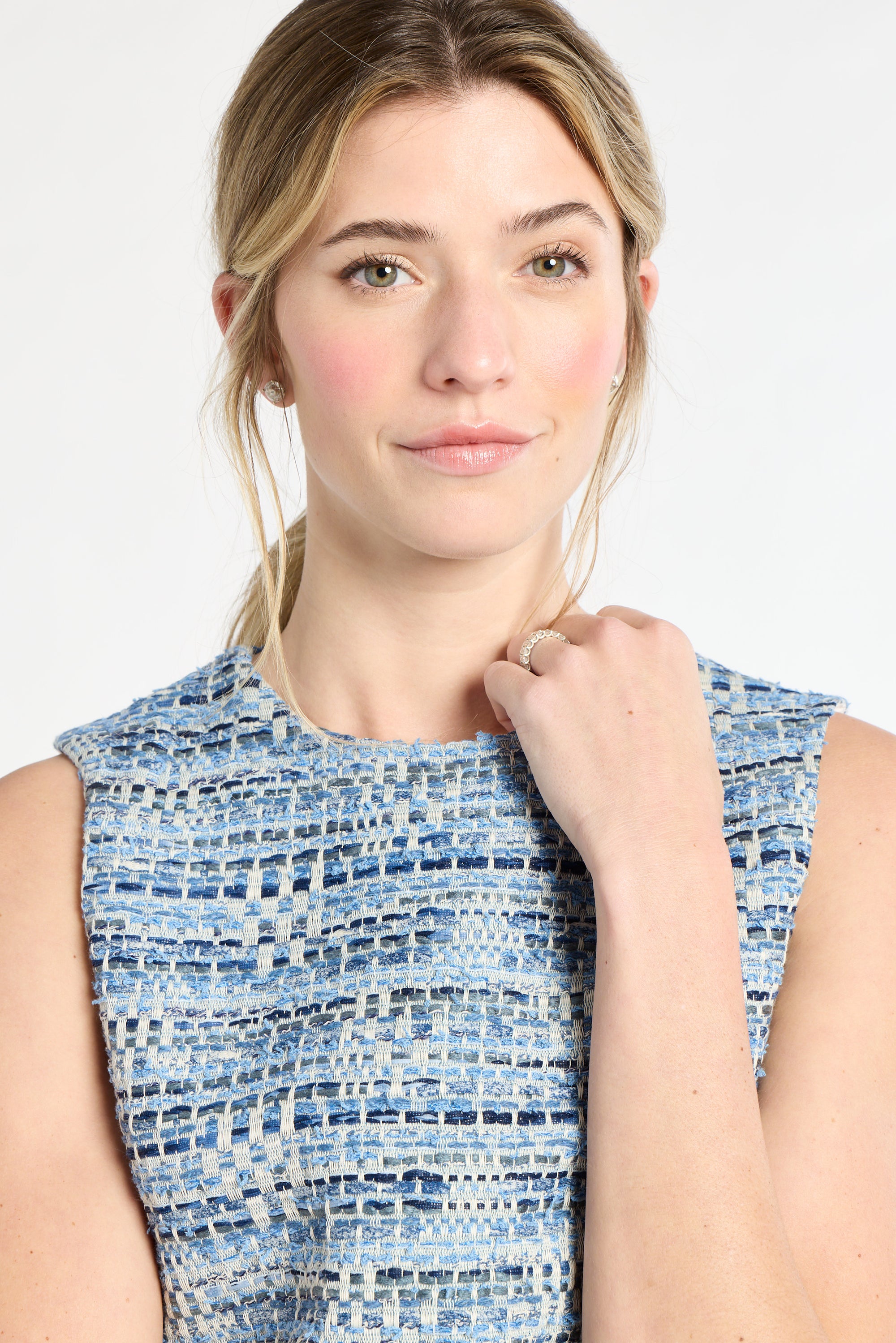 Woman wearing a blue tweed sleeveless top against a white background