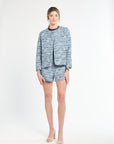 Woman wearing blue tweed blazer and matching shorts on a white background