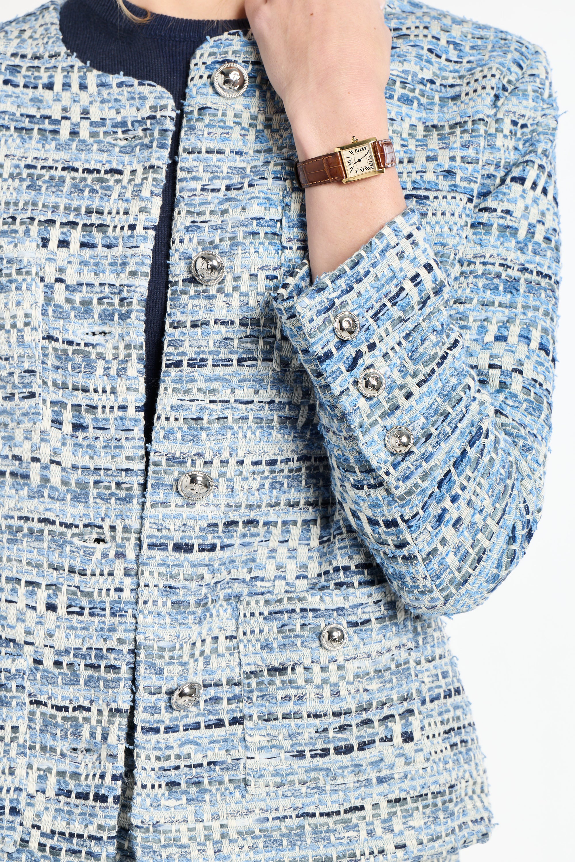 Close-up of a person wearing a blue tweed jacket with a watch on a white background