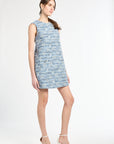 Side profile of a woman wearing a blue tweed dress on a white background