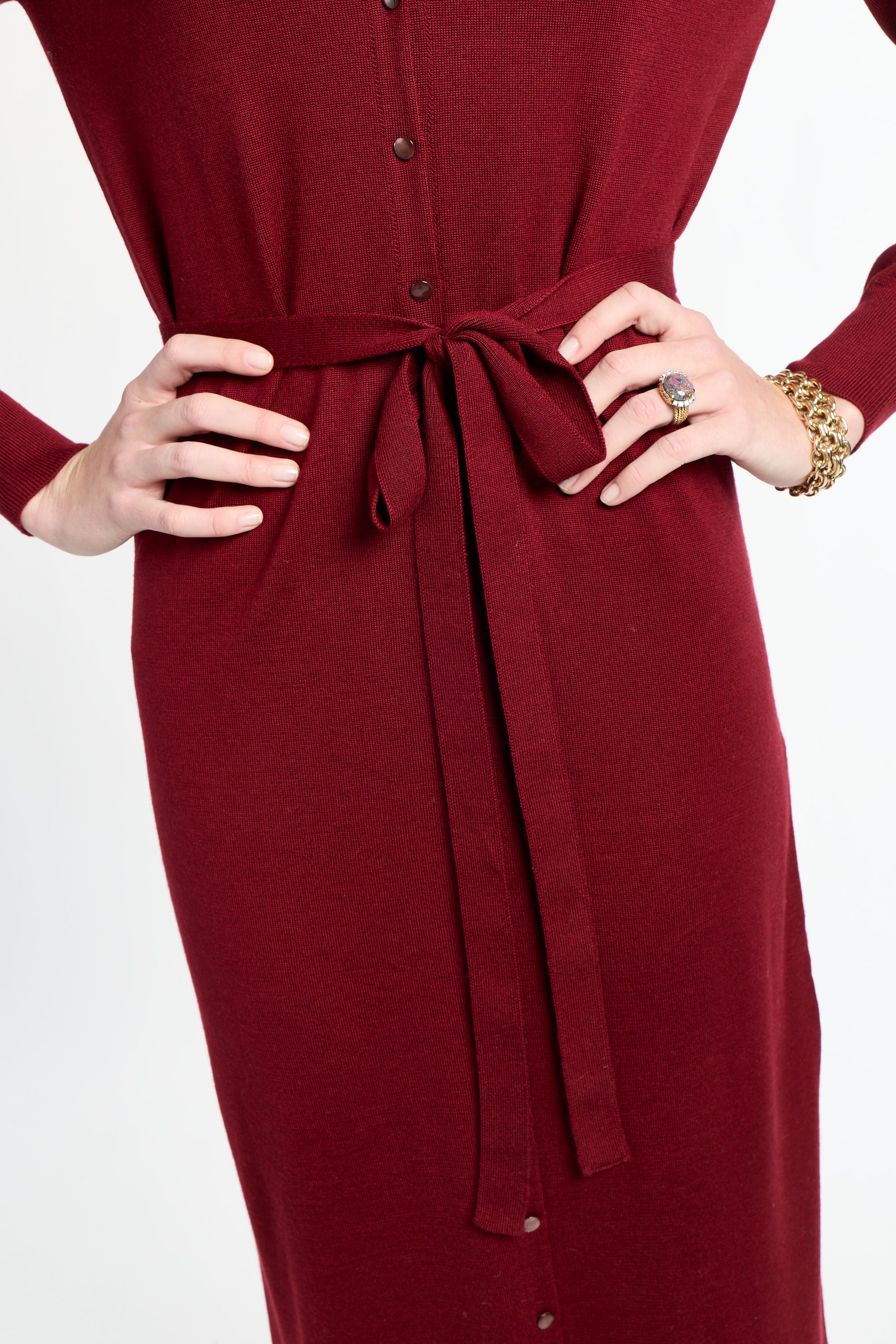 Red dress with a belt being adjusted on a white background