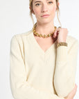 Woman wearing a cream sweater and gold jewelry on a white background