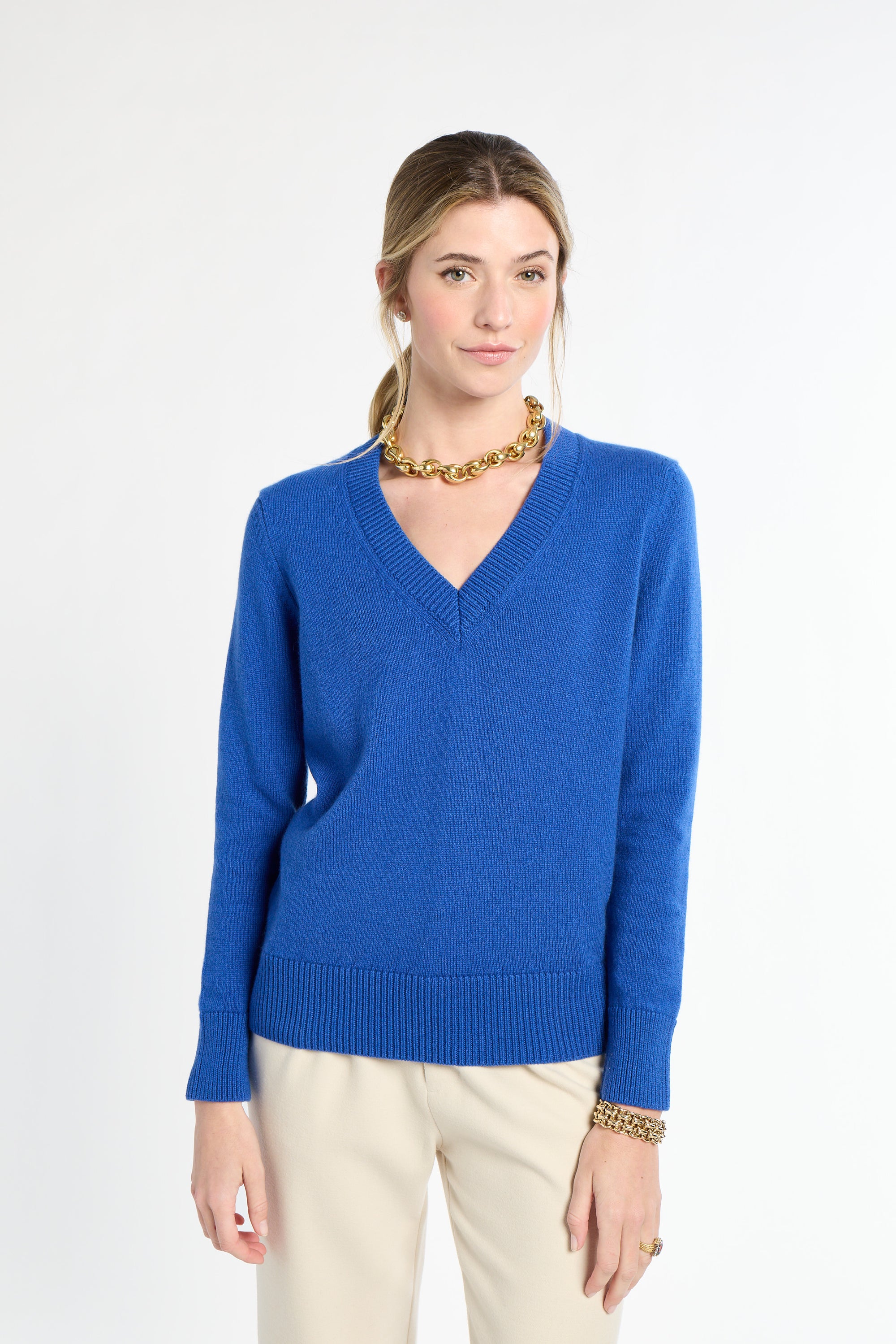 Woman wearing a blue sweater and beige pants on a white background