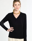 Woman wearing a black sweater and gold necklace on a white background