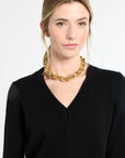 Woman wearing a black sweater and gold chain necklace on a white background