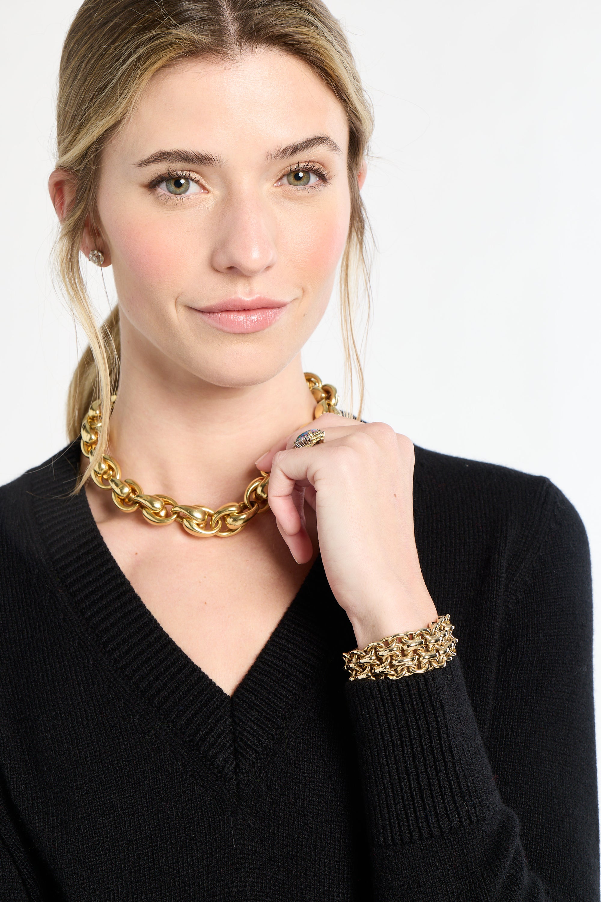Woman wearing a gold chain necklace and bracelet on a white background