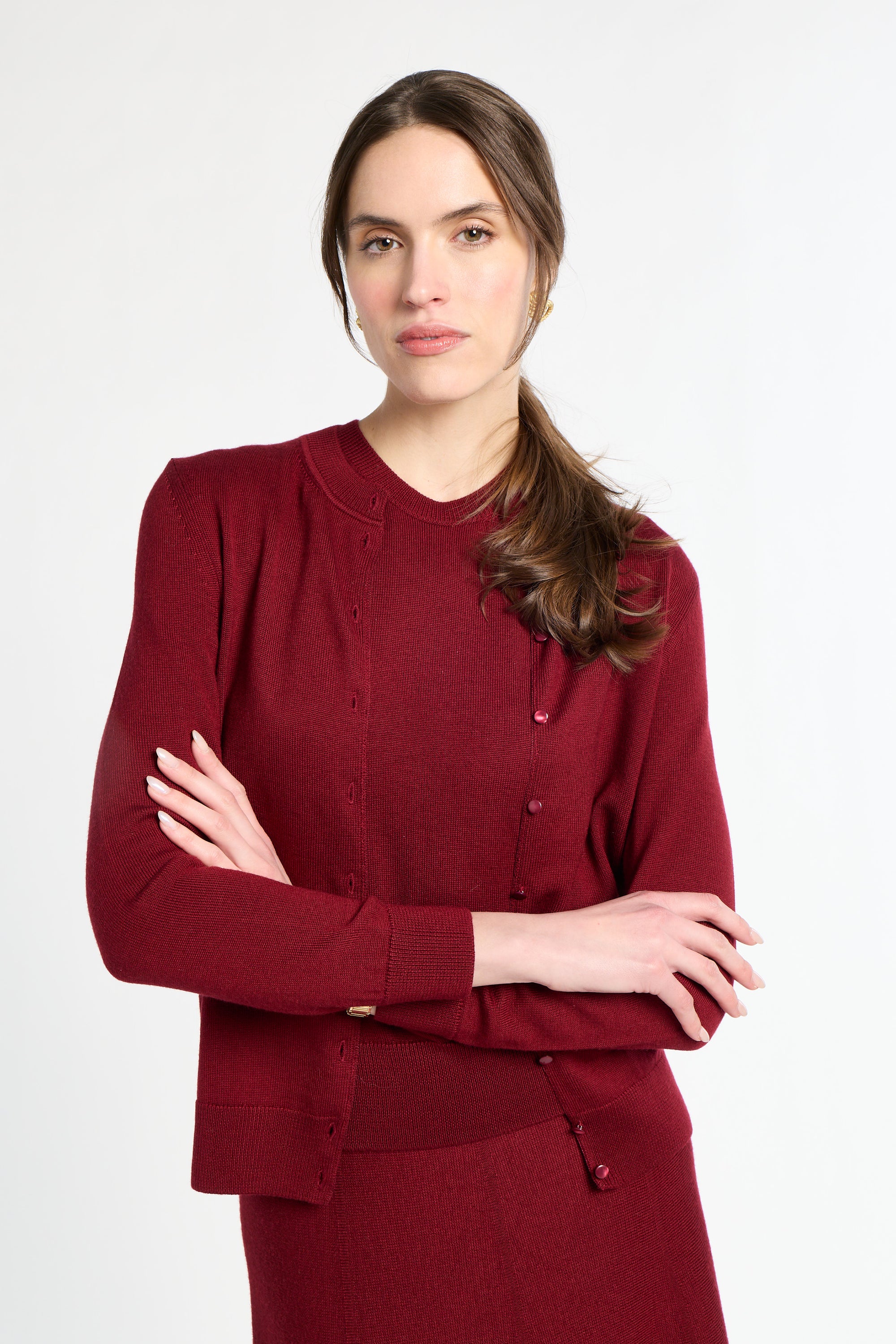 Woman wearing a burgundy outfit with a matching cardigan and skirt on a white background