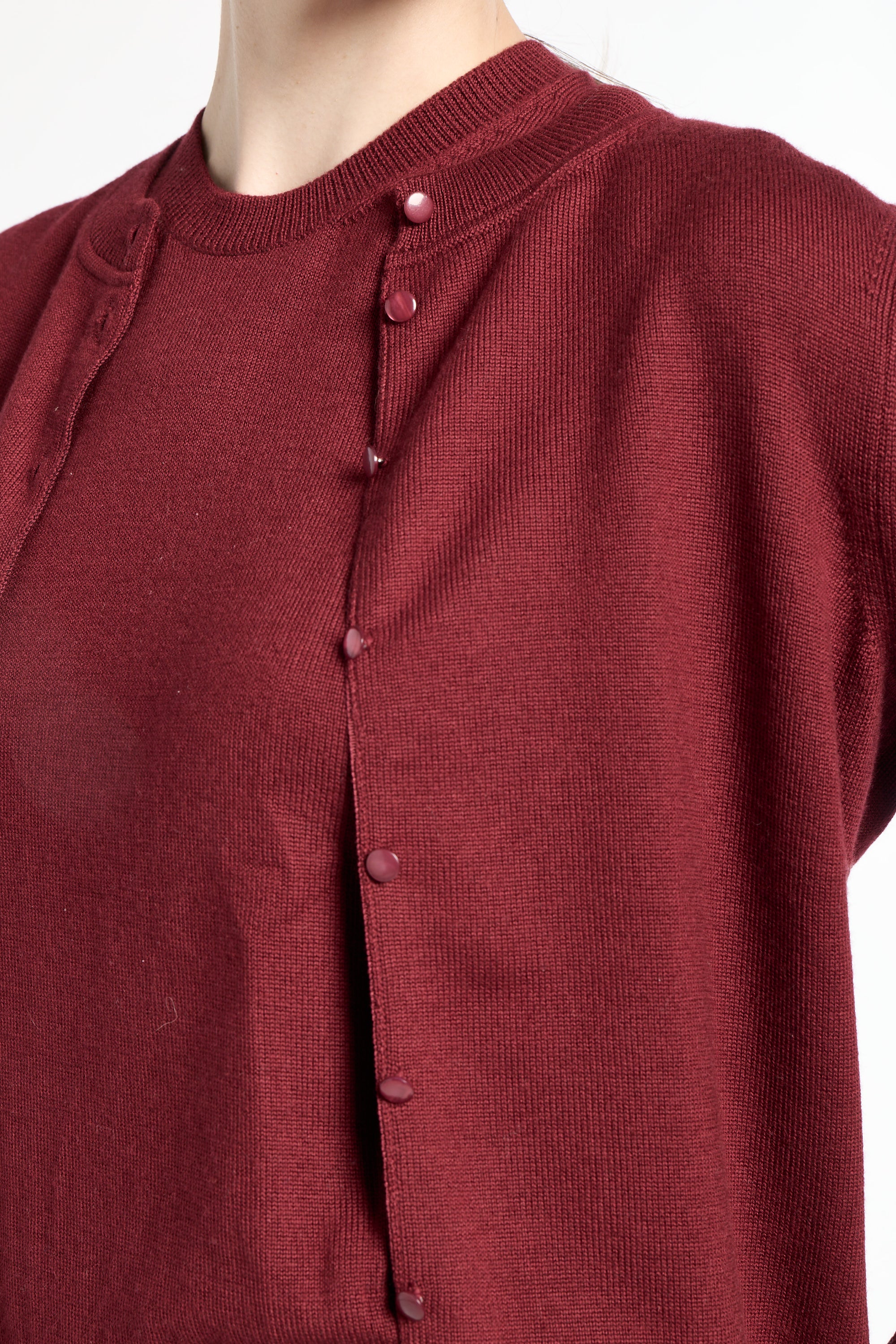 Close-up of a maroon cardigan with buttons on a white background
