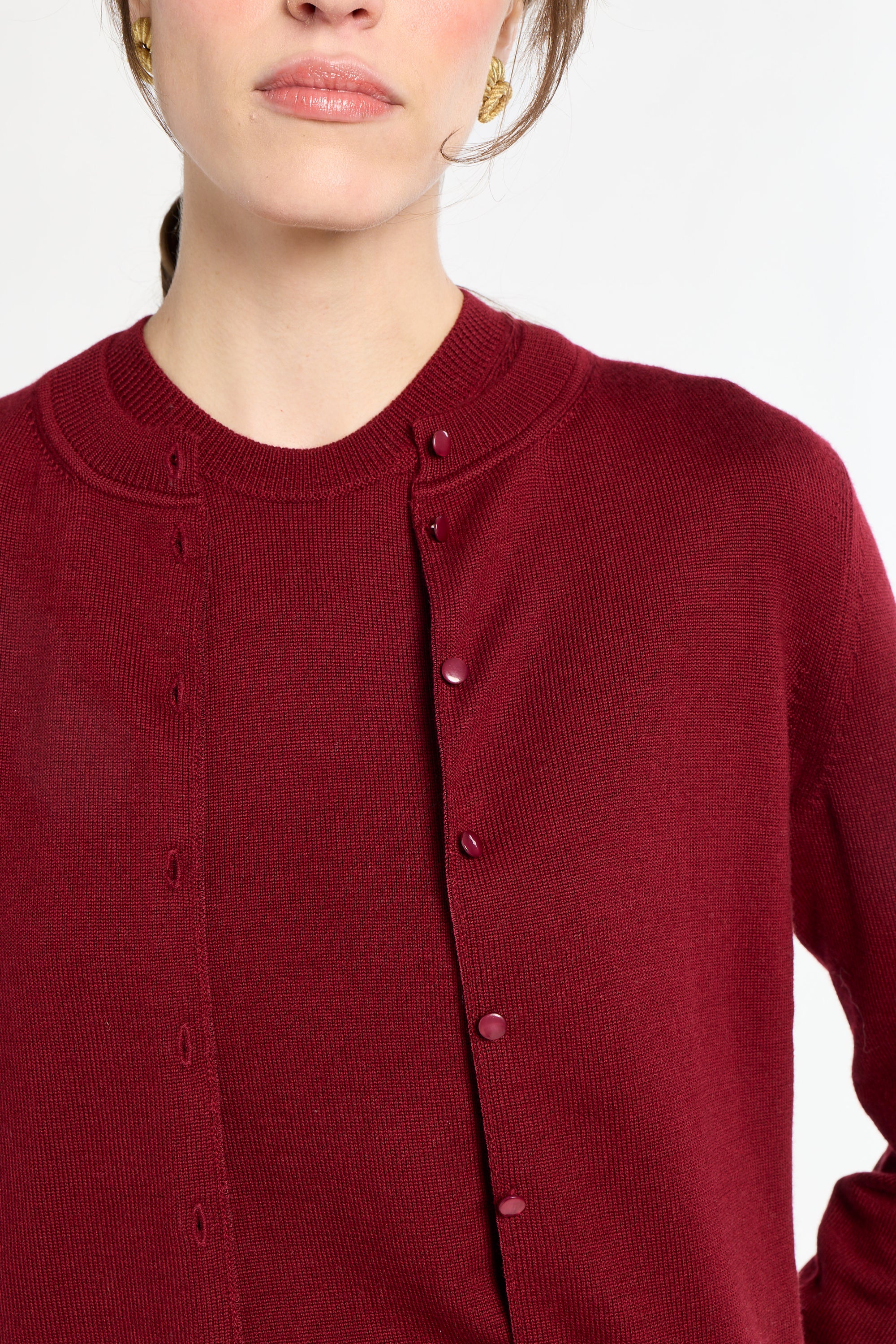 Close-up of a person wearing a red cardigan with a plain background