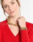 Woman wearing gold jewelry including a necklace, bracelet, and ring on a white background