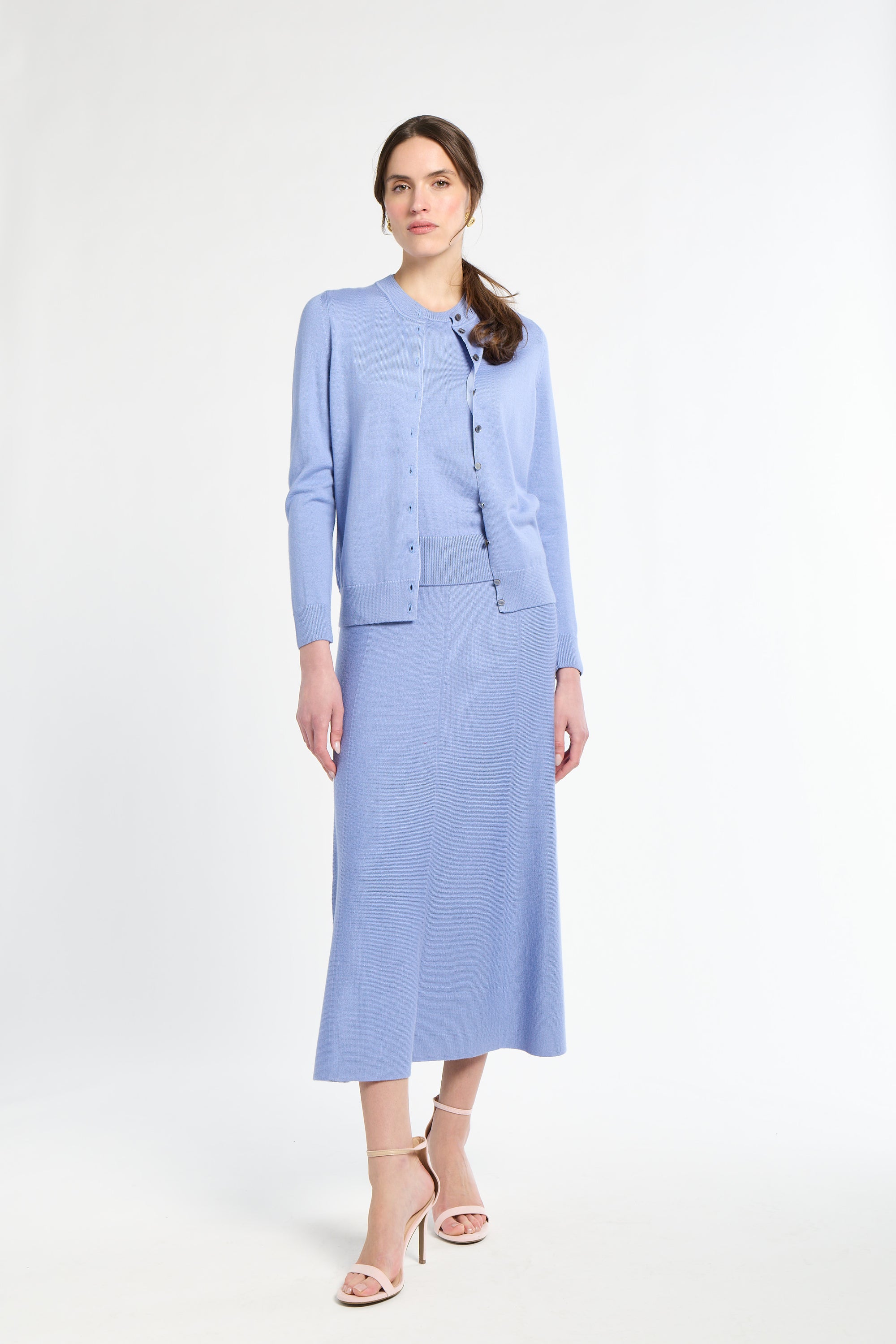 Woman wearing a light blue suit with a jacket and skirt on a white background