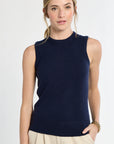 Woman wearing a navy sleeveless sweater against a white background